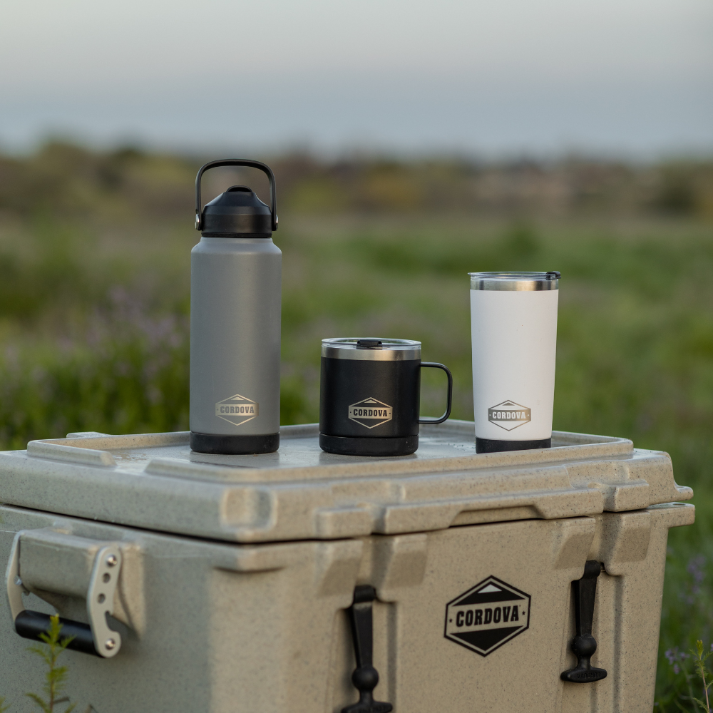 Drinkware Bundle with a gray handled bottle, black steel mug and white stainless steel tumbler, each bearing a logo